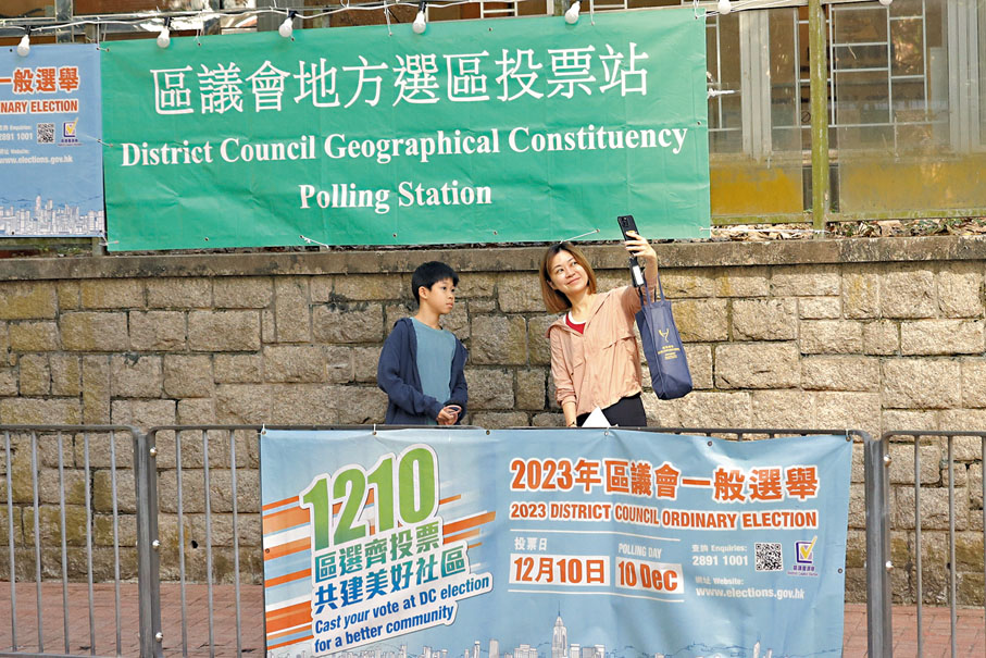 ◆市民以區選橫額作背景自拍，似為學童上一堂公民教育課。香港文匯報記者北山彥 攝