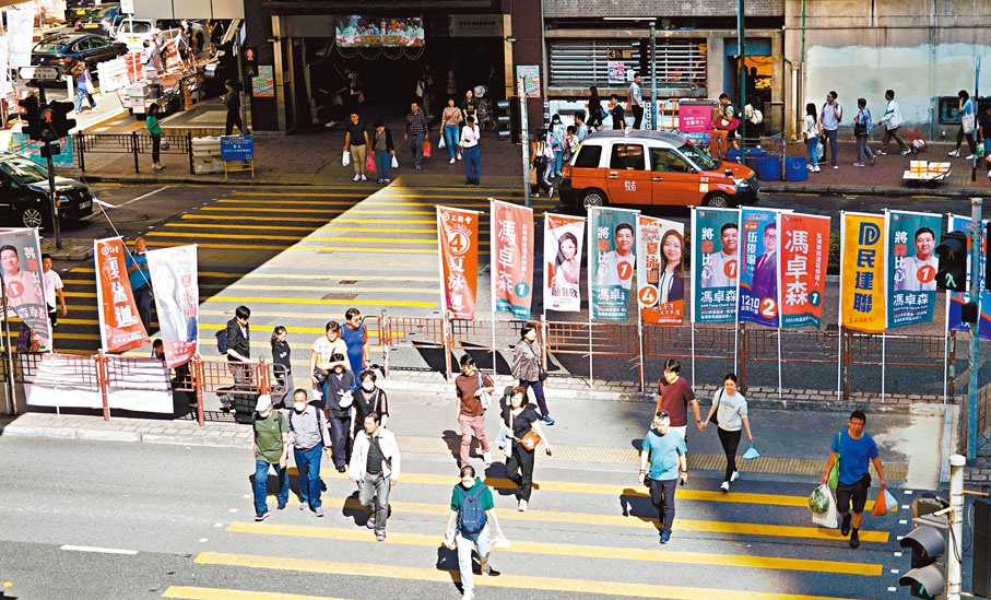 ◆荃灣東南選區一個紅綠燈位斑馬線，插滿候選人的旗旛。   香港文匯報記者曾興偉 攝