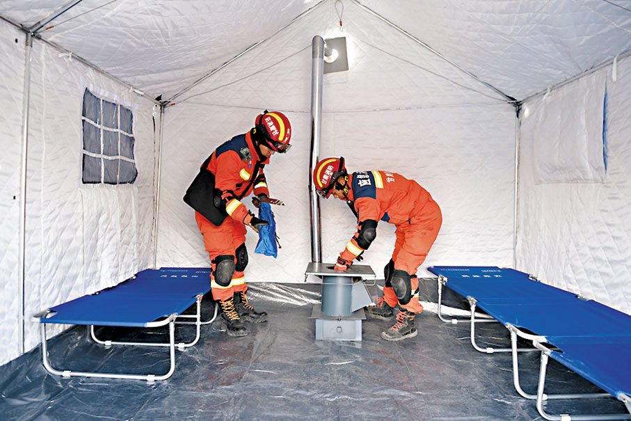 ◆在積石山縣大河家鎮大河村安置點，救援人員在安裝火爐。 新華社