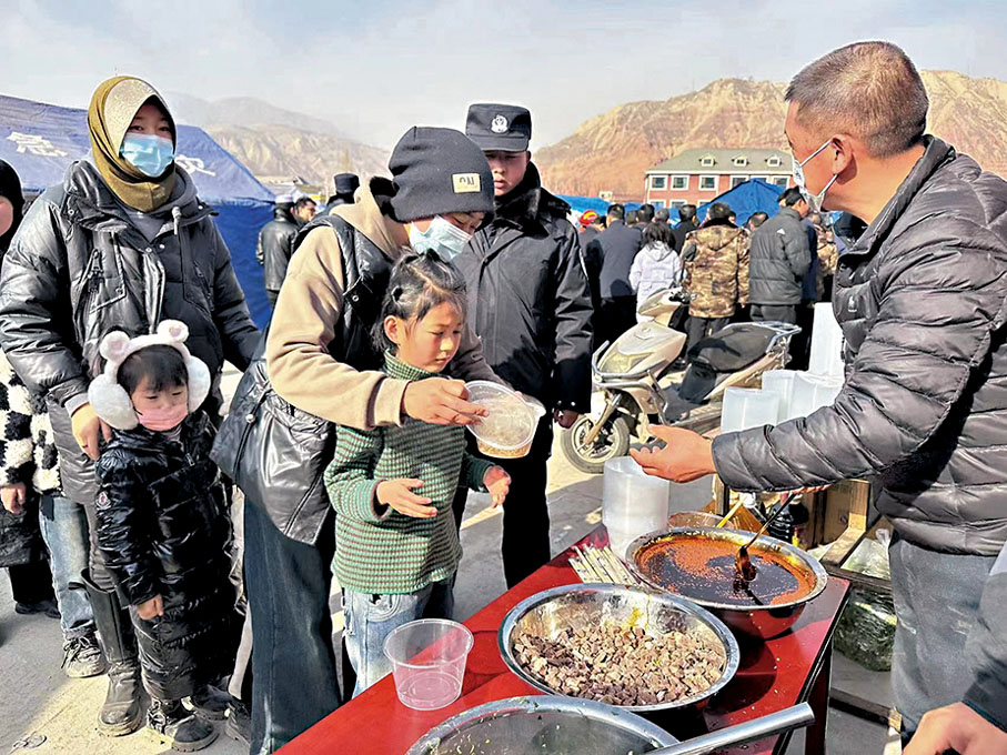 ◆12月19日，在積石山縣大河家鎮大河村安置點，受災群眾排隊取餐。 新華社