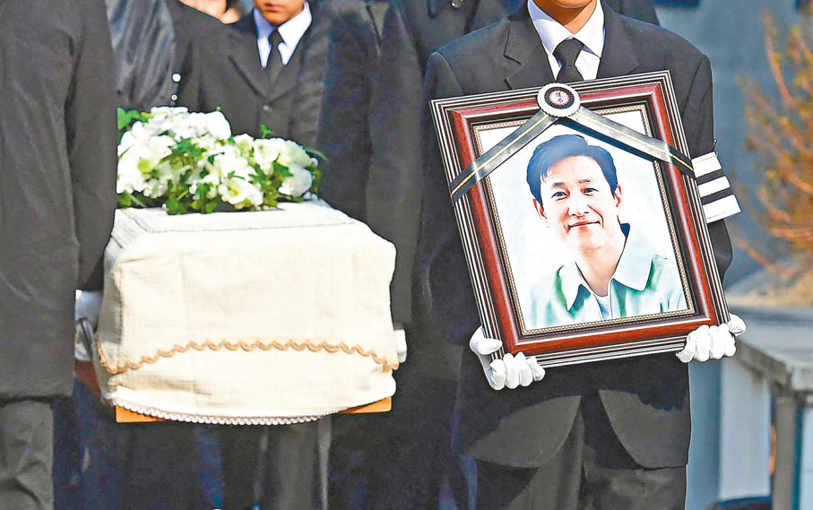 ◆李善均的兒子手捧父親遺像走在送殯隊伍前。 法新社