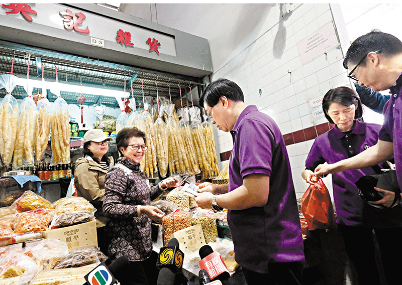 ◆李家超在沙頭角街市內的海味街與檔主英姐交談，了解店舖經營情況。香港文匯報記者涂穴 攝