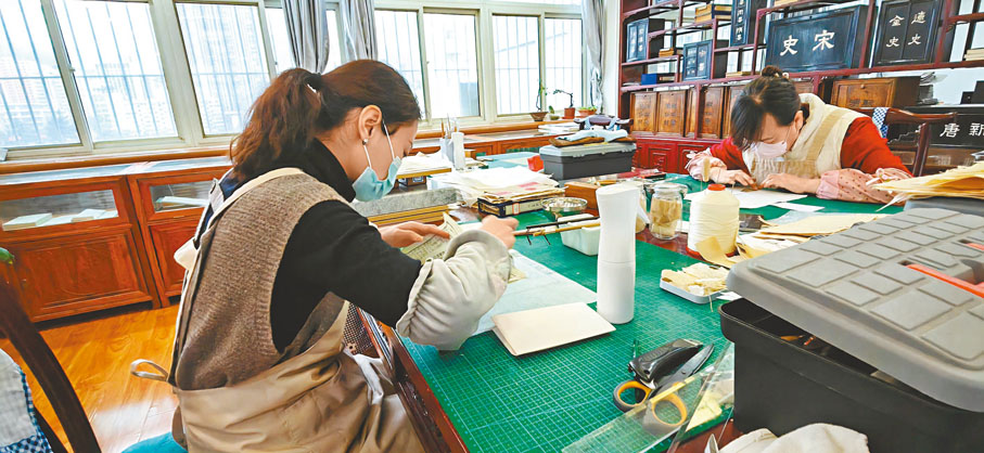 ◆姚嘉迪和同事們在修復古籍。 新華社