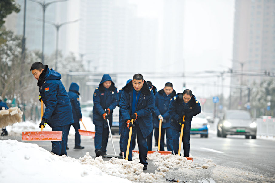 ◆在武漢市武昌區積玉橋，消防員們正在路面清理冰雪。香港文匯報記者歐陽思柔  攝