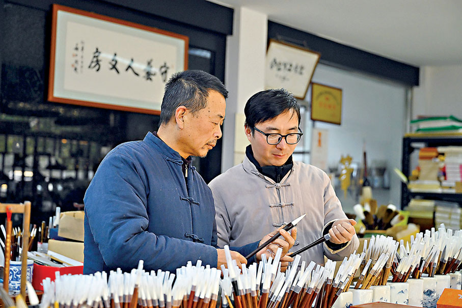 ◆佘吉(右)和父親佘征軍查看製作完成的宣筆。