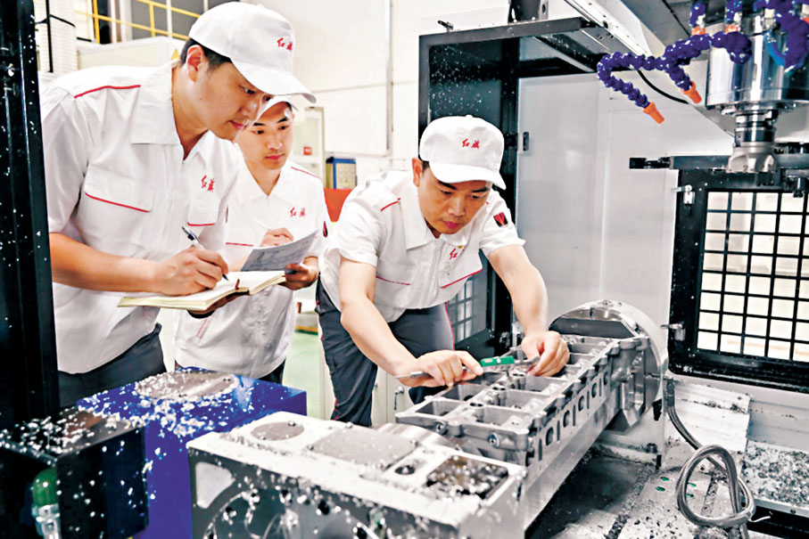 ◆楊永修（右）在中國一汽研發總院加工車間內檢查試製零部件的精度。 網上圖片