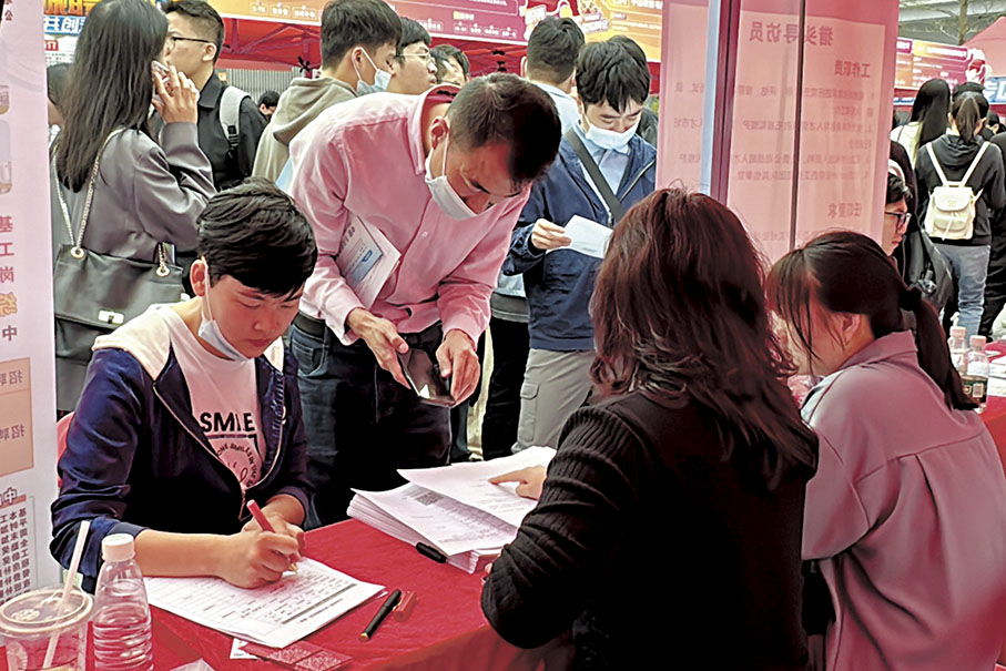 ◆2024「南粵春暖」大型招聘會上，一家香港勞務公司攤位前，有赴港工作意向的求職者正填寫求職簡歷。 香港文匯報記者李紫妍  攝