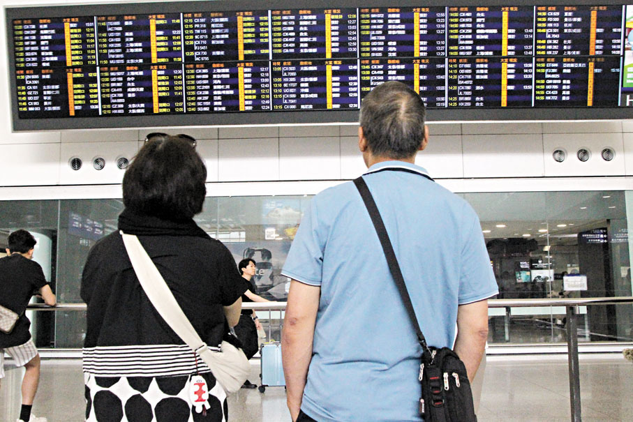 ◆有不少在台遊客提早結束旅程，搭乘飛機返回香港。圖為旅客查看抵港航班狀況。 香港文匯報記者黃艾力  攝