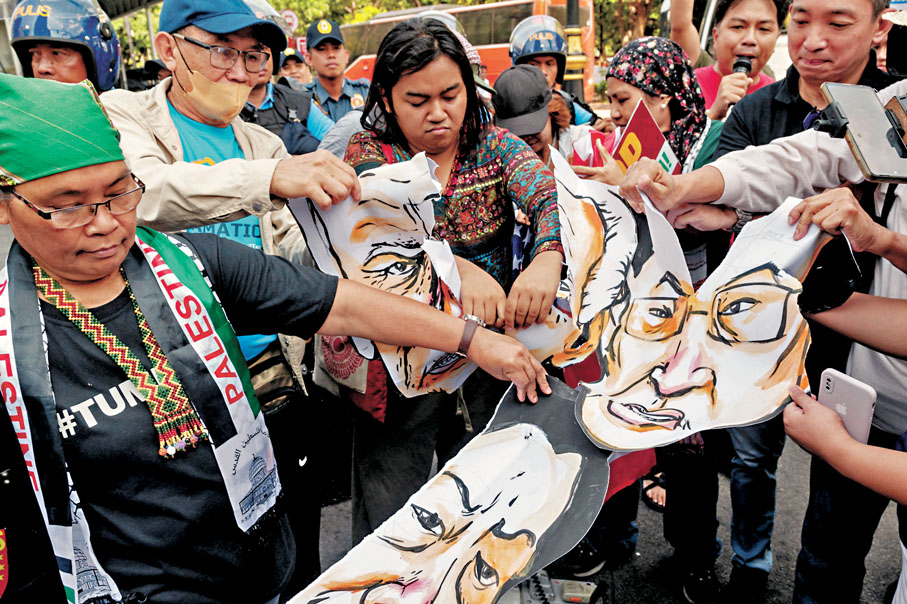 ◆有菲民抗議峰會，撕毀拜登、岸田及馬科斯的肖像畫示威。  路透社