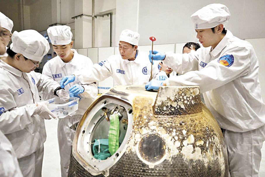 ◆2020年12月17日，在中國航天科技集團五院，科研人員打開嫦娥五號返回器艙門，取出裝有月球樣品的容器並進行稱重。 資料圖片