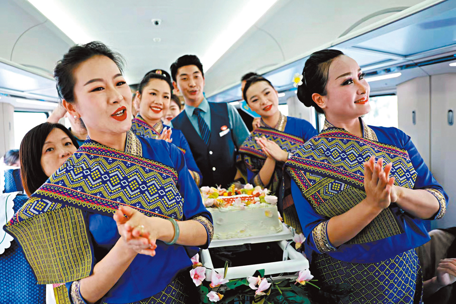 ◆13日，工作人員與乘客慶祝中老鐵路國際旅客列車開通一周年。 香港文匯報雲南傳真