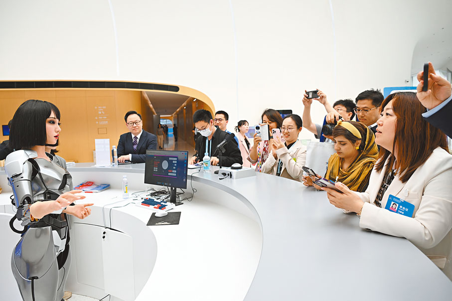 ◆4月25日，2024中關村論壇年會在北京開幕。圖為人們與中關村國際創新中心諮詢台的仿生人形機器人互動。中新社