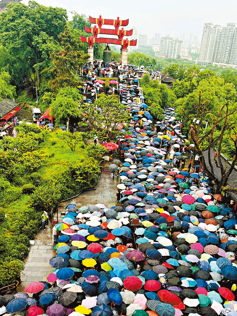 ◆遊客打着雨傘排隊登黃鶴樓。 網上圖片
