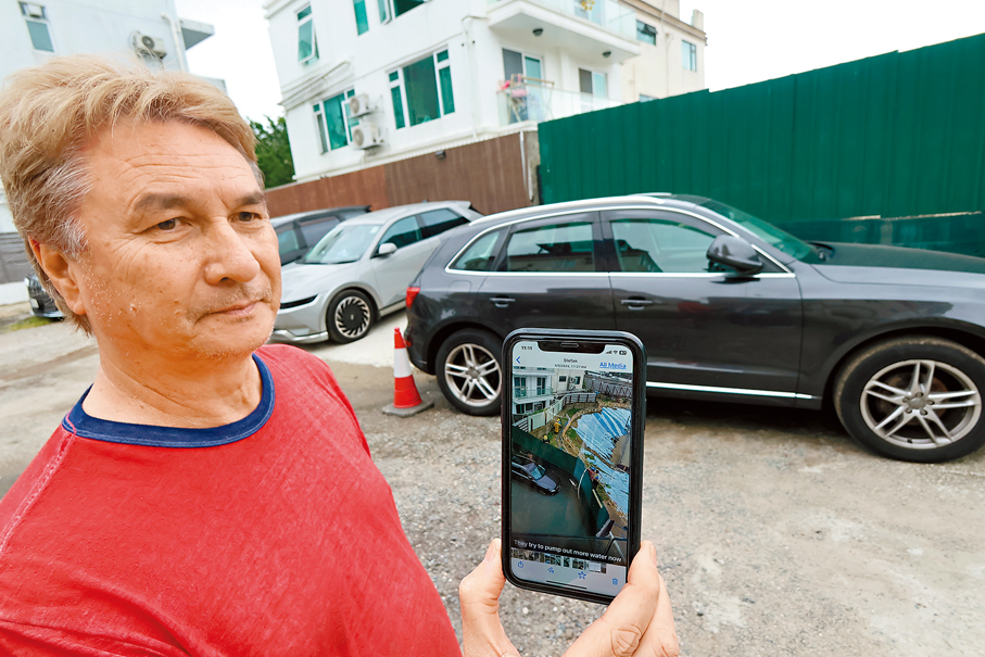 ◆David展示地盤圍板阻擋水流，雨水已浸至車門位置。 香港文匯報記者涂穴  攝