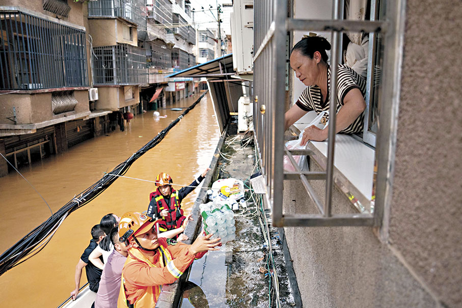 ◆6月18日至今，湖南平江縣遭遇自有氣象紀錄以來持續時間最長、強度最大、雨量最多的嚴峻汛情。圖為7月2日，在平江縣大橋西路附近，消防員給被困群眾運送物資。 新華社