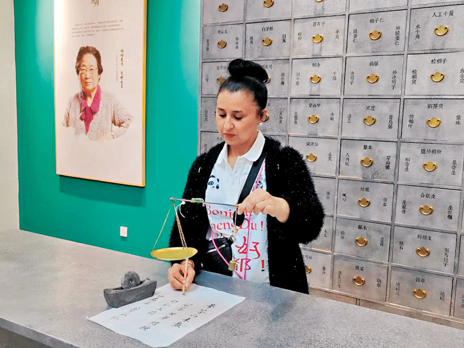 ◆一名法國中醫藥愛好者在稱量中藥材。  新華社