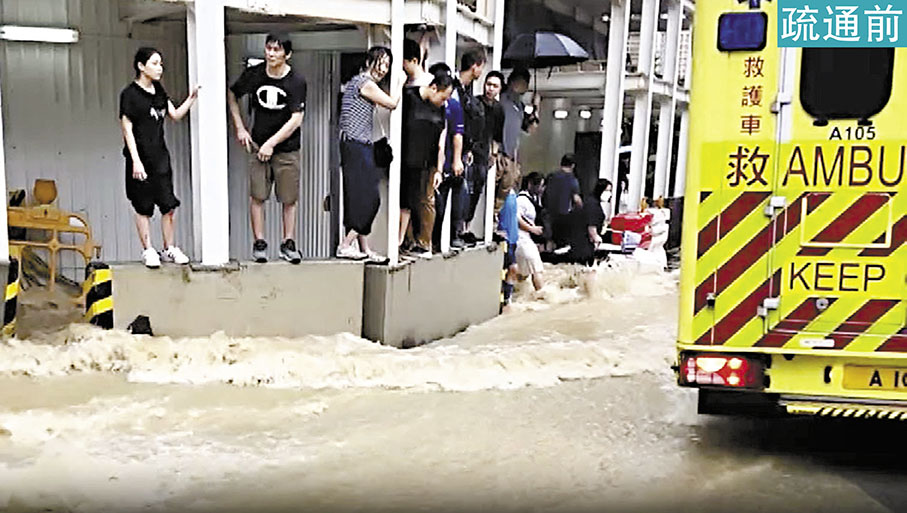 ◆黃雨下，聯合醫院擴建地盤對開的秀茂坪道不斷有泥水湧出，行人紛紛站上石壆等待救援。 電視截圖