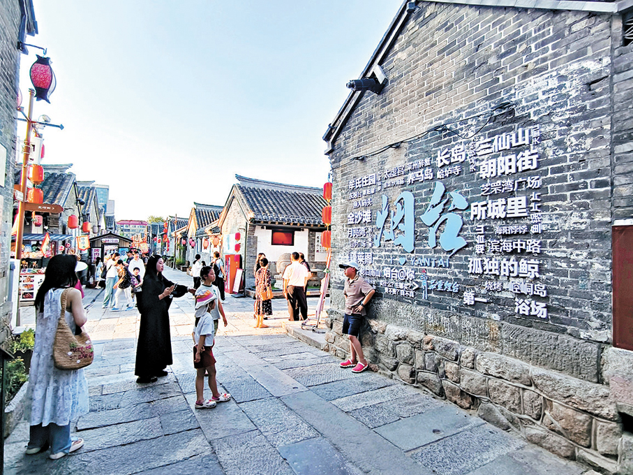 ◆ 遊客在「所城里」景點牆前打卡拍照。