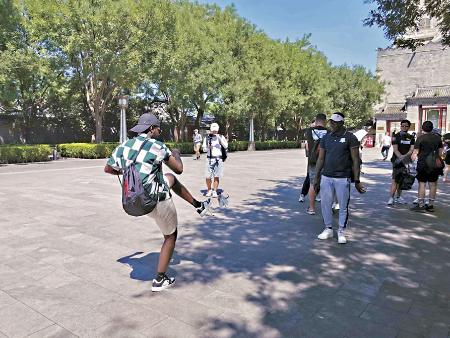 ◆外國遊客跟北京當地人一同踢毽子。