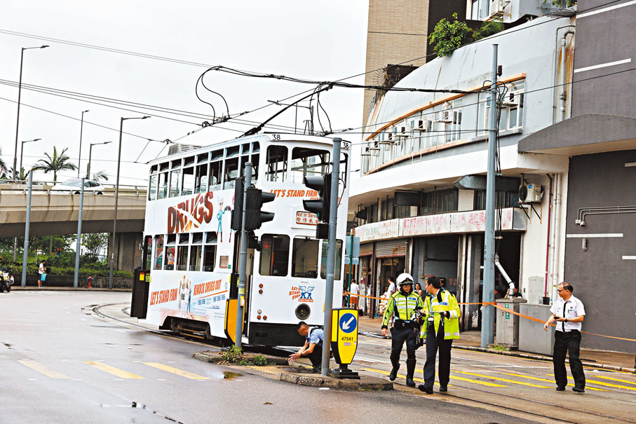 ◆老翁偕兩外孫女和一名印傭在堅尼地城橫過馬路時，遭一輛電車撞倒。圖為警方現場調查。香港文匯報記者鄧偉明 攝