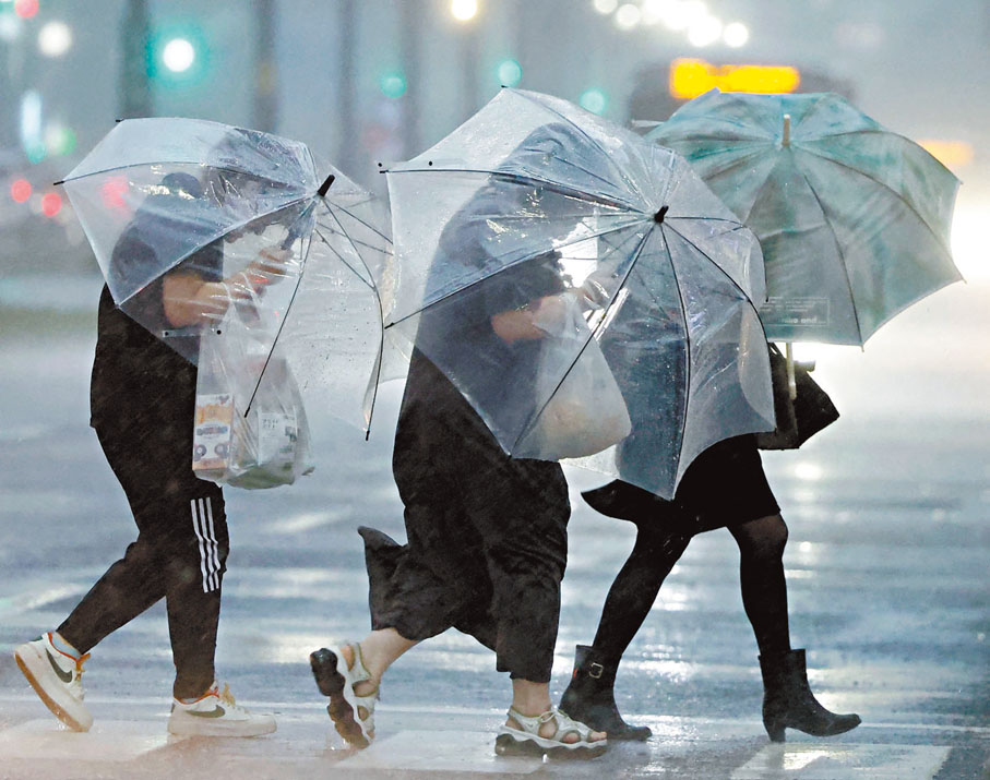 ◆鹿兒島居民撐着雨傘，在行人路逆風而行。 路透社