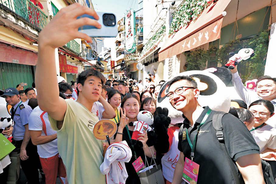 ◆潘展樂參觀澳門福隆新街步行區時和工作人員、遊客自拍。   中新社