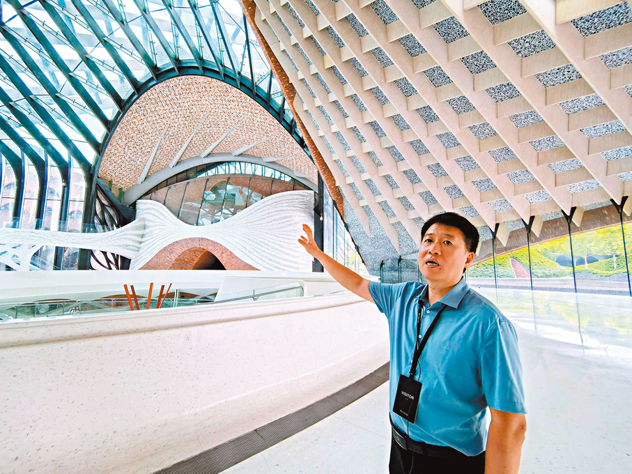 ◆江蘇華建總經理吳碧橋向記者介紹瑪絲菲爾總部大廈的建築特點。 香港文匯報記者李望賢 攝