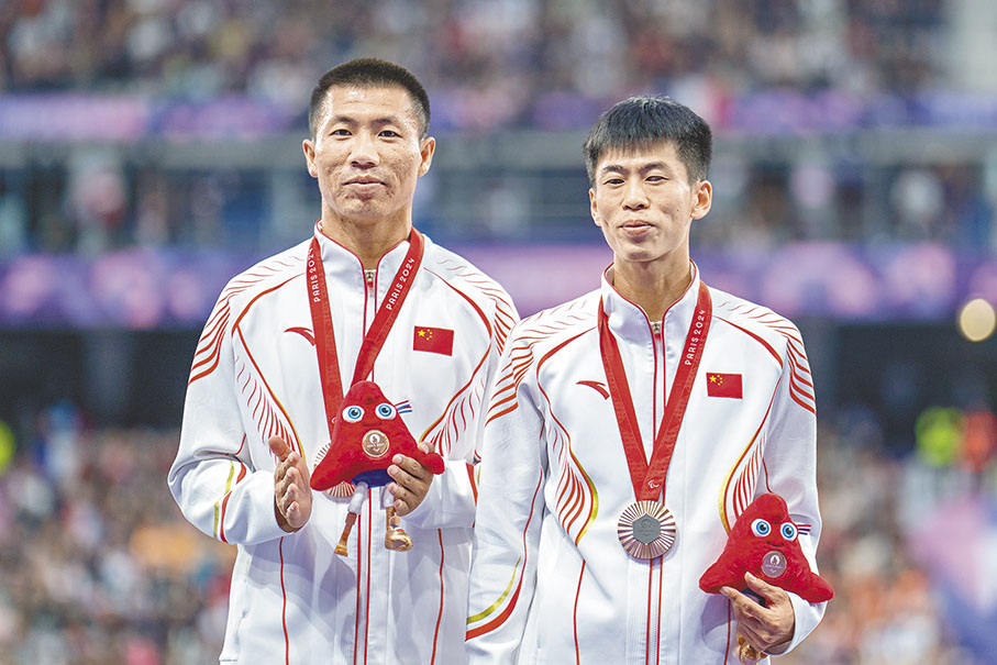 ◆邸東東(右)5日在男子100米T11級決賽以11秒08成績獲得銅牌。圖為他與領跑員廉佳庚在頒獎儀式上。   新華社