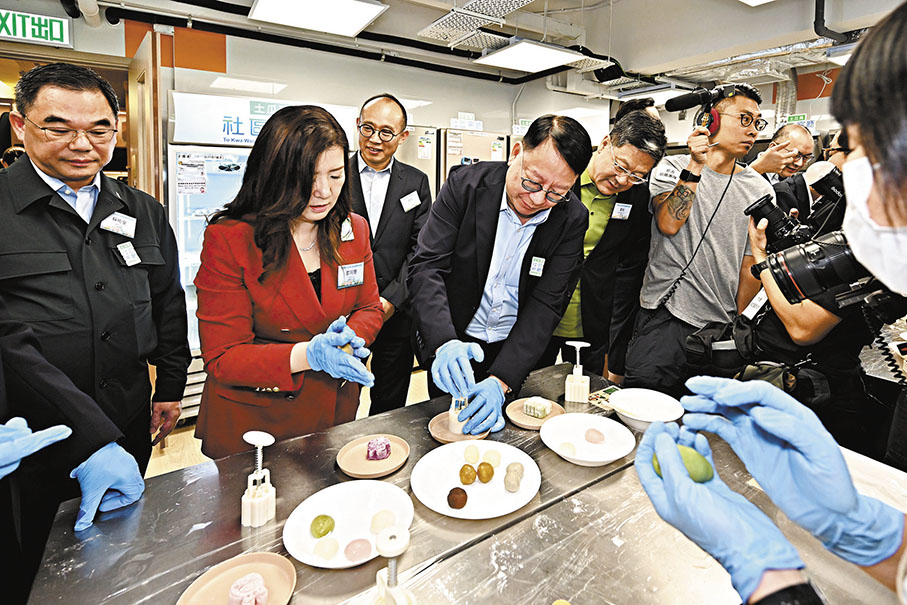 ●陳國基（左四）在共享備餐間與受惠家庭製作月餅。