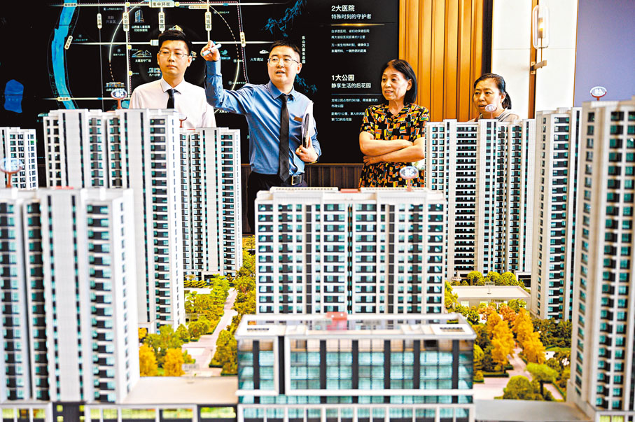 ●中共中央政治局昨日召開會議研究部署經濟工作，強調要促進房地產市場止跌回穩。圖為山西太原一售樓部銷售人員向民眾推介商品房戶型。資料圖片