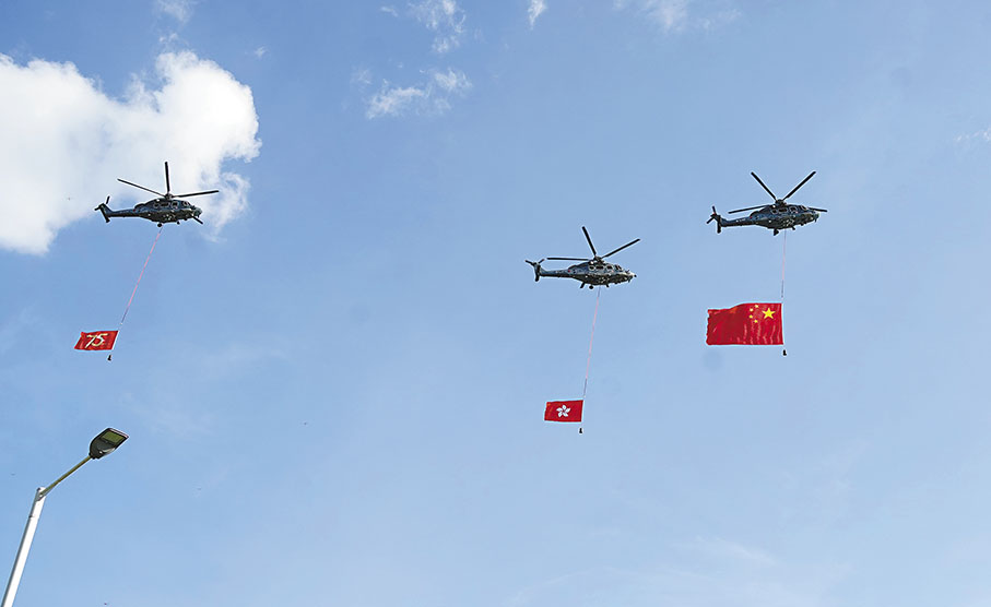 ●特區政府飛行服務隊三架直升機懸掛着國旗、區旗和「75」周年旗幟，飛過維多利亞港上空。 香港文匯報記者曾興偉  攝