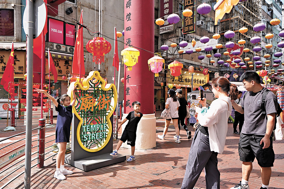 ●有旅客「一家大細」到廟街拍照打卡。香港文匯報記者 曾興偉 攝