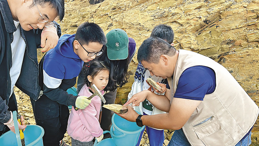 ●來到雲南省古生物研究重點實驗室科研科普基地，大人孩子一起化身「化石獵人」，沉浸體驗化石挖掘。圖為挖到化石以後找專家鑒定。   香港文匯報記者譚旻煦  攝
