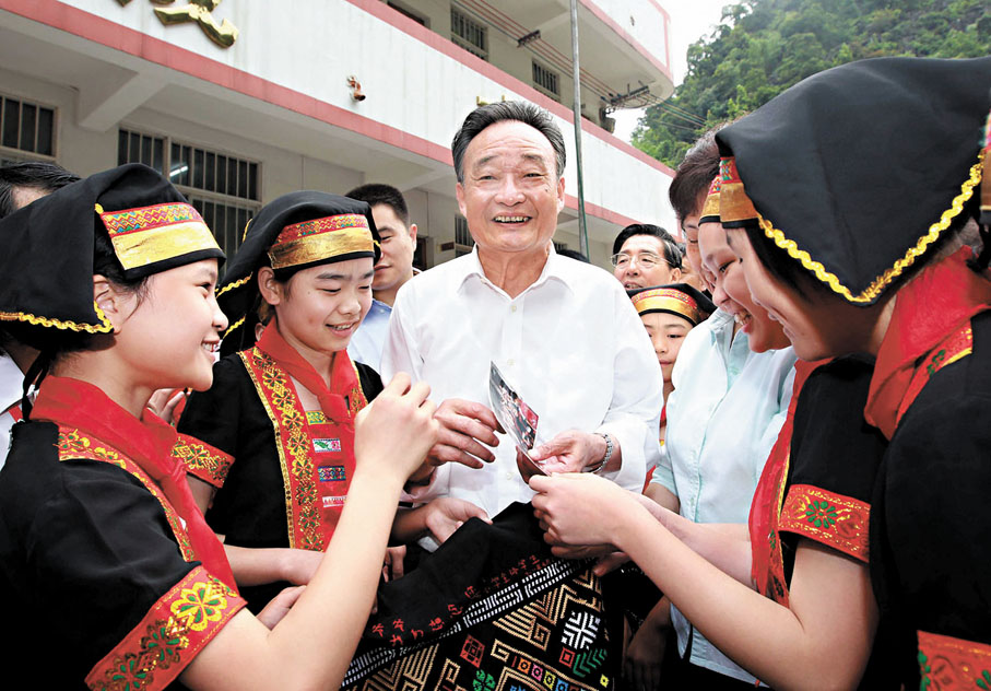 ●2011年4月28日至29日，中共中央政治局常委、全國人大常委會委員長吳邦國在廣西壯族自治區百色市田東縣調研。這是4月29日，吳邦國驅車數十公里來到田東縣作登瑤族鄉偏僻的隴窮屯看望村民時，和小學生們一起交談。吳邦國看到山寨村民的生活比以前大有改善，十分高興。資料圖片