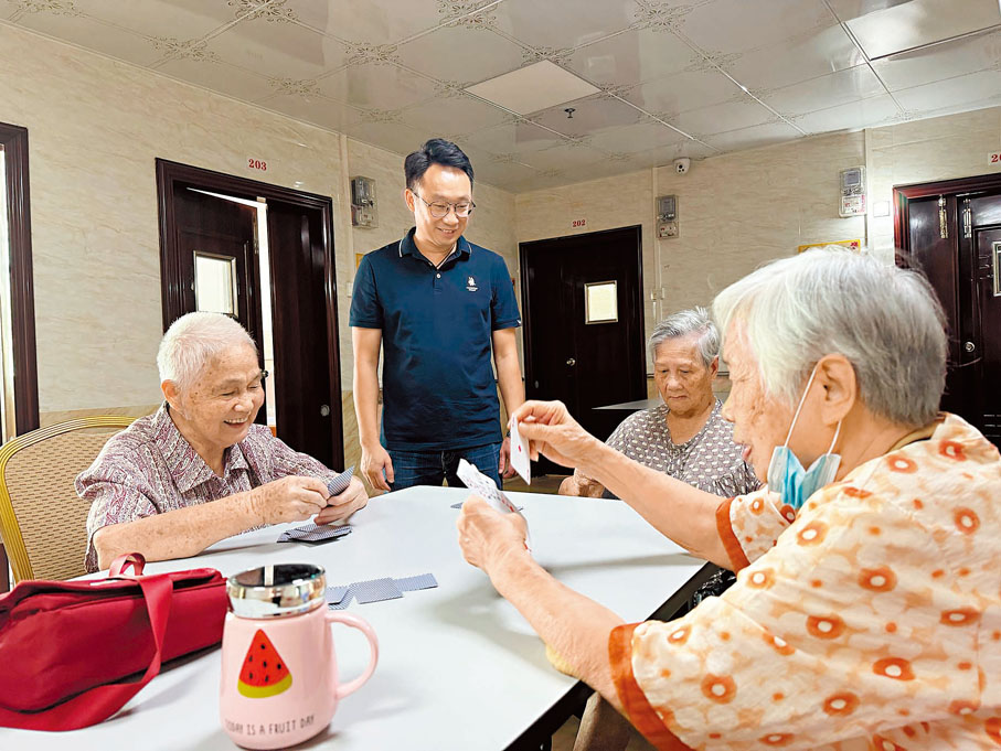 ●彭錫開（站立者）在和打牌的老人家聊天。 香港文匯報記者盧靜怡 攝