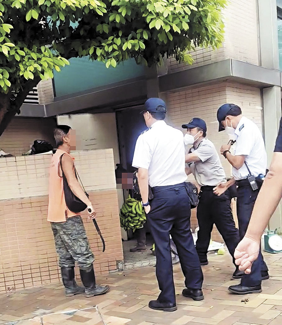 ●小販在地上拾起一把鐮刀，阻礙食環署人員執法。 Fb影片截圖
