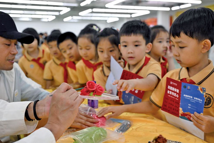 ●強化「家校社」協同育人，是建設教育強國的重要要求。圖為2024年5月，北京第二實驗小學聯合北京烹飪協會食育工作專委會開展「職趣新體驗 食育傳匠心」家校社協同育人迎「六一」特色活動。 （新華社）