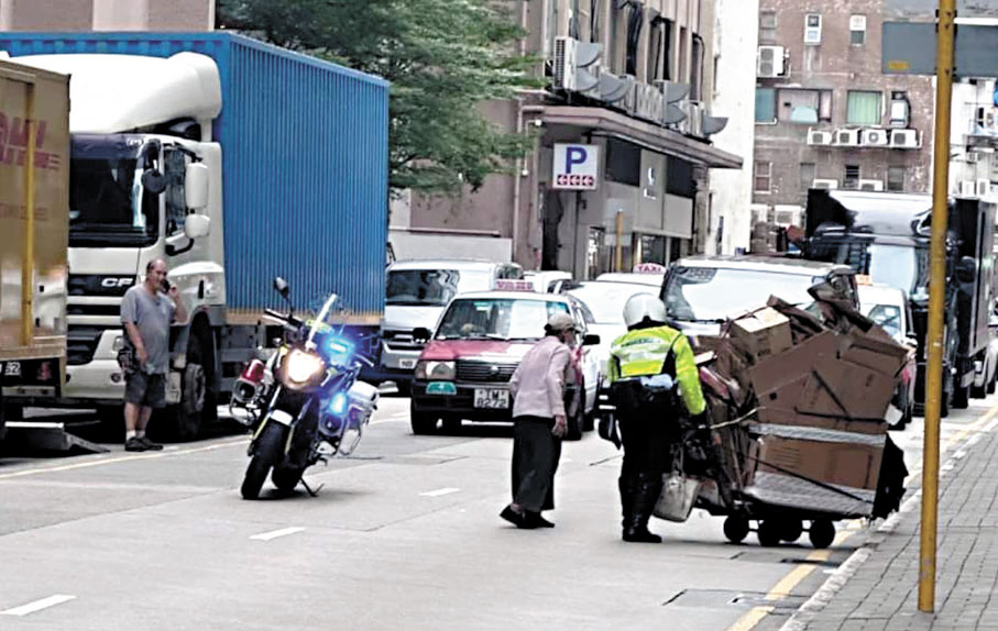 ●警員黃松燃在觀塘幫助執紙皮婆婆，被熱心市民拍下相片及向警務處致送讚揚信。 資料圖片