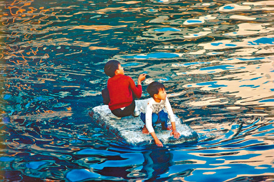 ●上環海旁，兩名小孩划着一塊浮板。 攝影師：艾思滔