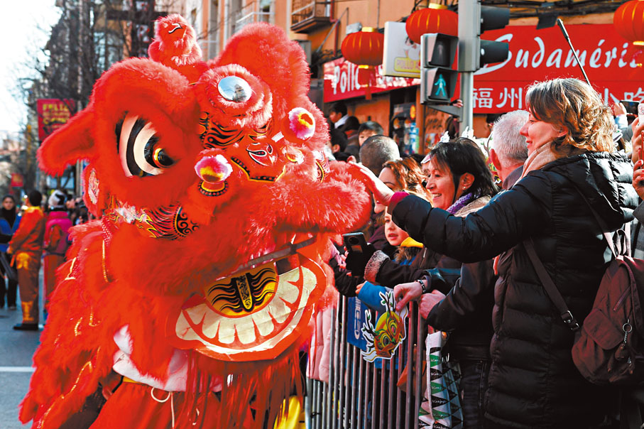 ●春節民俗活動已走進全球近200個國家和地區。圖為 2月11日，在西班牙馬德里，龍年春節慶祝活動現場人們與舞獅演員互動。 資料圖片
