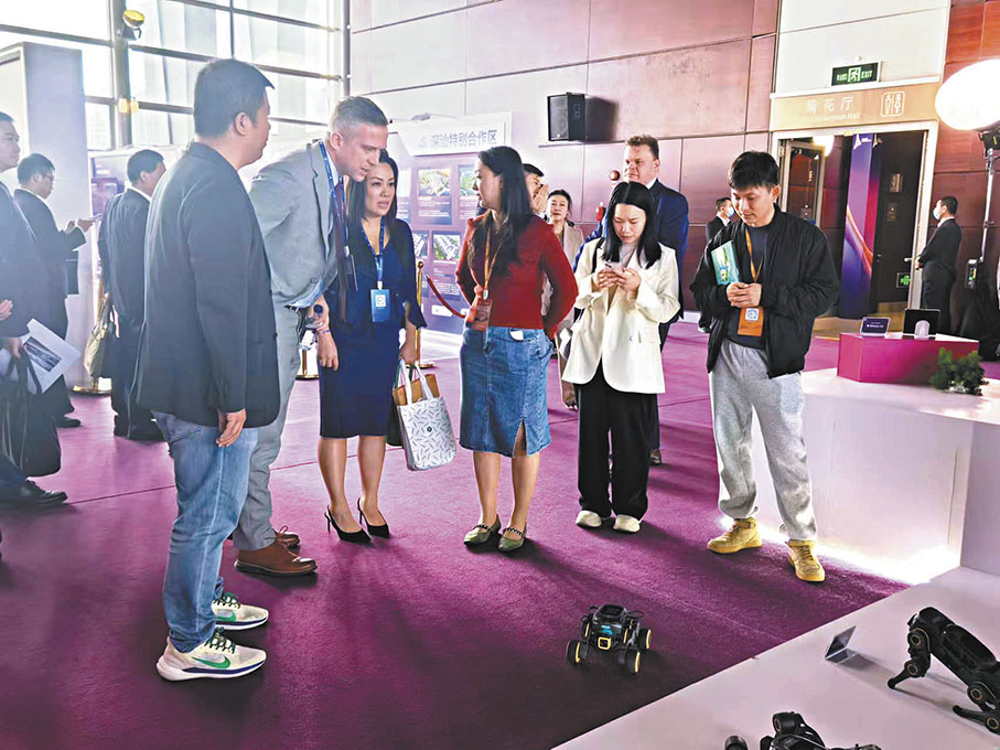 ●2024深圳全球招商大會設置了「招商走廊」和深圳品牌展示區。圖為現場展示的機器人吸引外資企業代表。 香港文匯報記者李望賢 攝