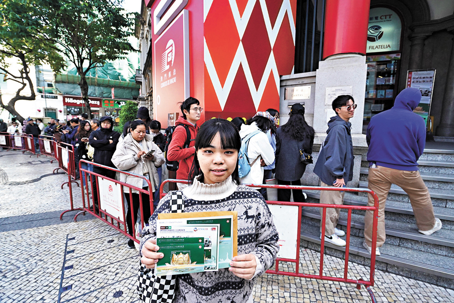 ●市民在澳門郵政總局外展示購得的紀念郵品。另可見其身後有長長人龍。 香港文匯報記者曾興偉 攝