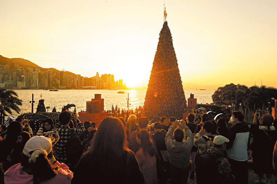 黃金冬日●市民與遊客聚集在西九聖誕樹下，感受在夕陽下的另類聖誕氣氛。香港文匯報記者郭木又 攝