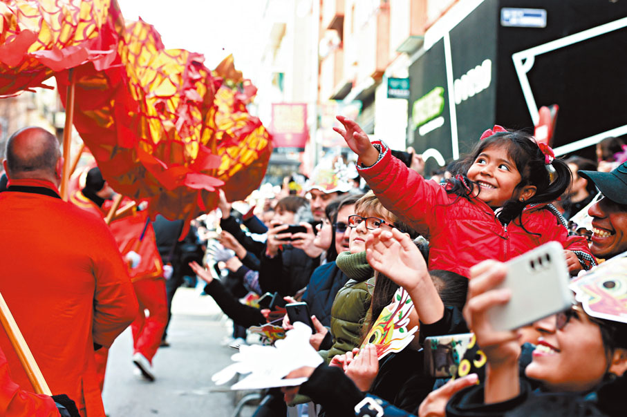 ●中國44項目列入世遺。圖為西班牙馬德里一名女孩與舞龍表演隊互動。 資料圖片