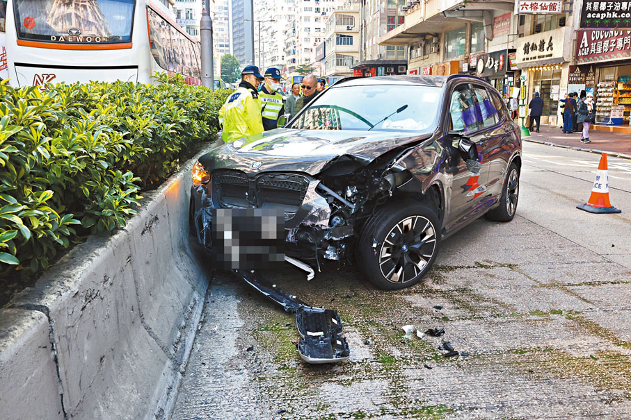 ●肇事寶馬私家車剷上行人路，再反彈馬路撞到石壆停下，警員到場調查。 香港文匯報記者劉友光  攝