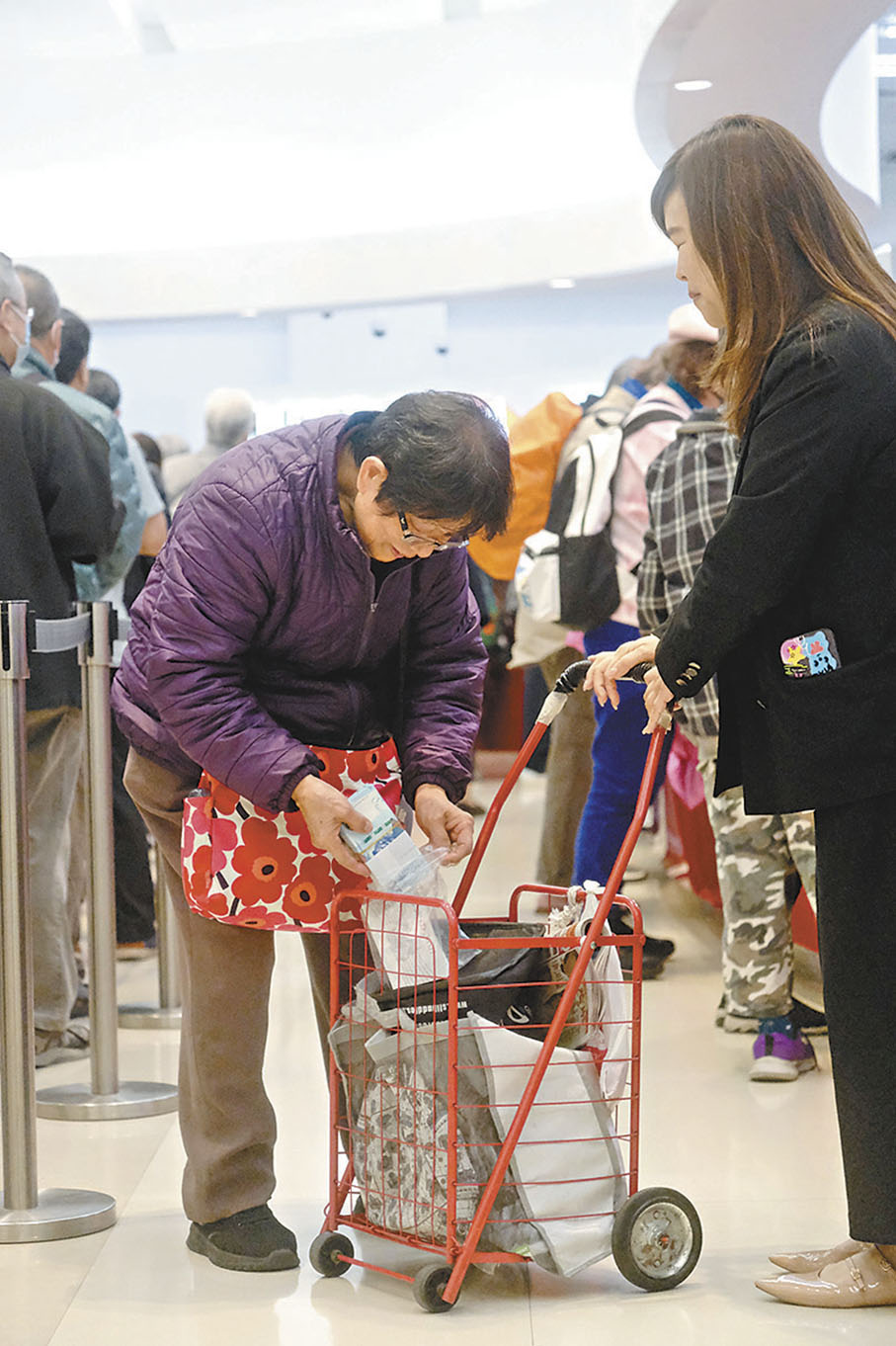 ●有長者將剛兌換的整疊新鈔，放進手推車。 資料圖片
