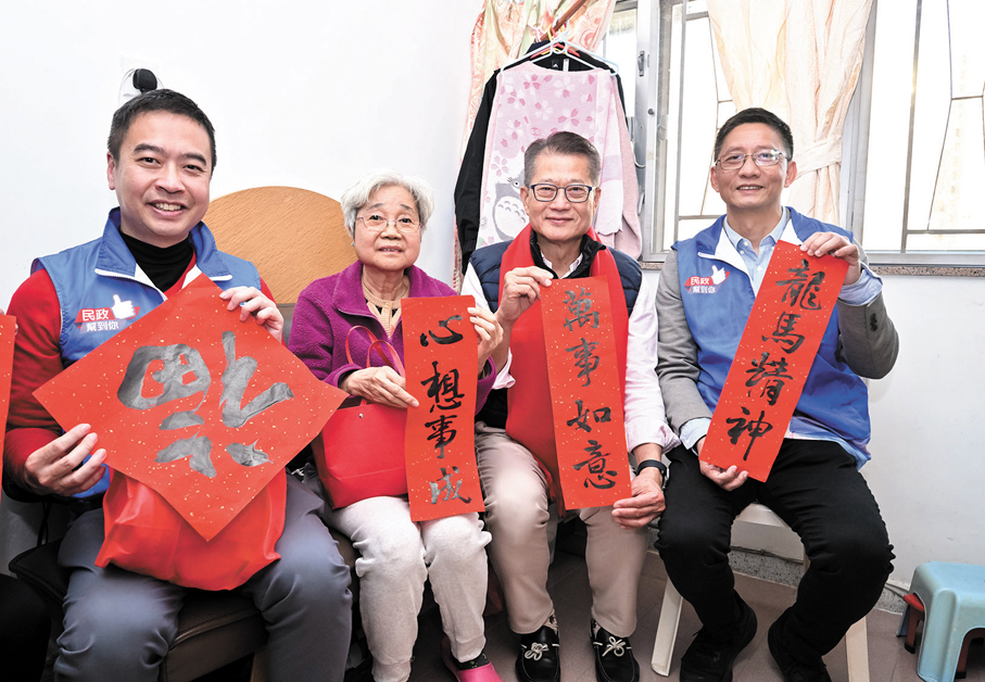 ●陳茂波(右二)昨日向家訪的居民送上賀年禮袋和揮春。