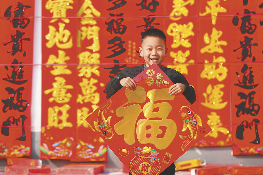 ●蛇年新春將至,「福」字往往與春聯一起走進百姓家。圖為一名小朋友在山東一年貨市場上展示新購買的「福」字。 新華社