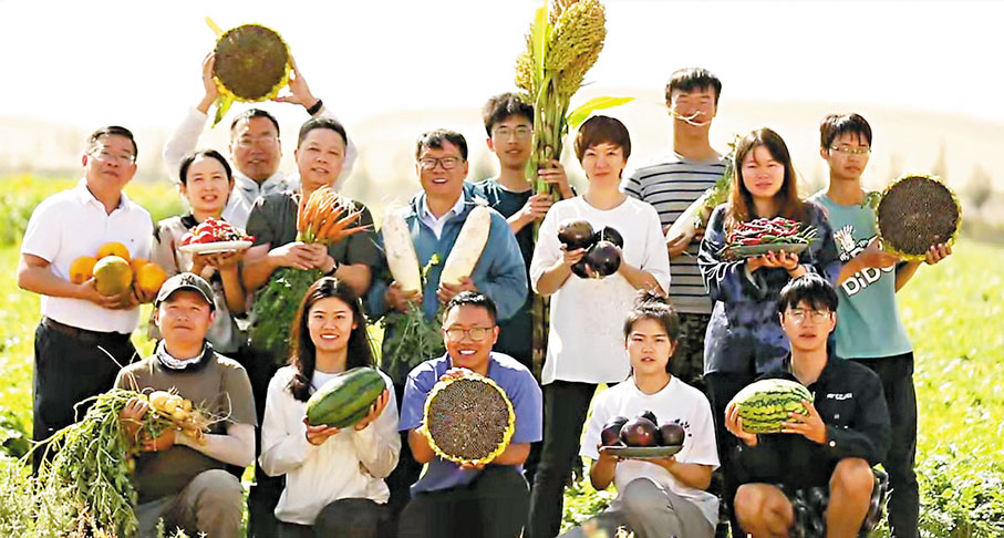 ●易志堅教授(第二排左四)和團隊舉起在烏蘭布和沙漠種植出的農作物開心合影。
