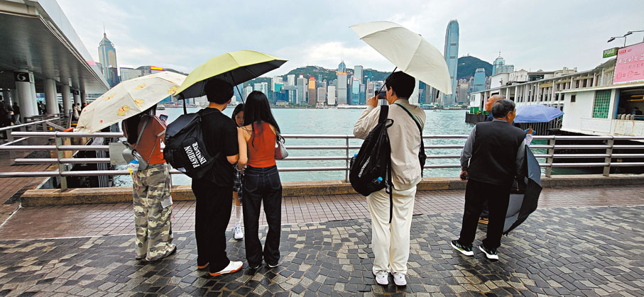 ● 仍有人冒雨在尖沙咀海旁打卡。香港文匯報記者鄧偉明  攝